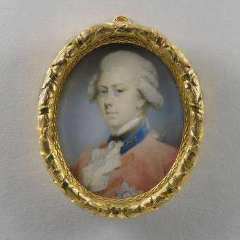 A miniature portrait of the young George IV in a gold frame. He has a solemn expression, powdered hair, and wears a red military uniform with blue collar, white cravat, and the Star of the Order of the Garter pinned to his breast. The frame has a decorative leaf pattern.