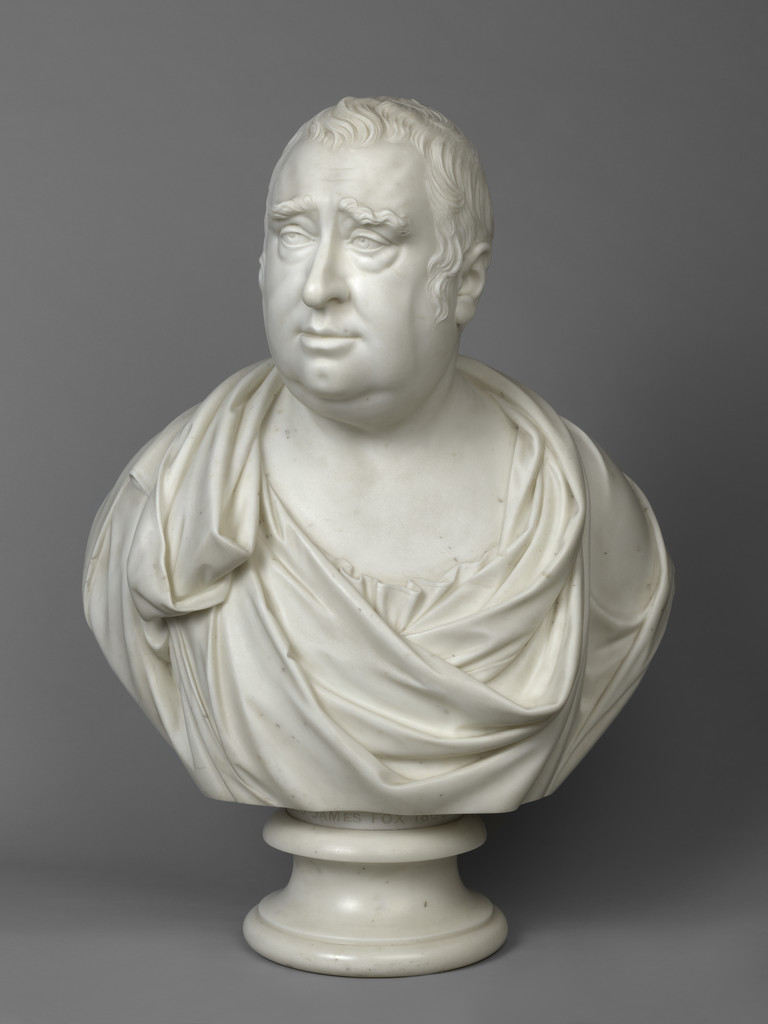 A marble bust of a man, Charles James Fox, with a toga-like garment draped over his shoulders. He has heavy jowls, prominent eyebrows and a thoughtful expression.